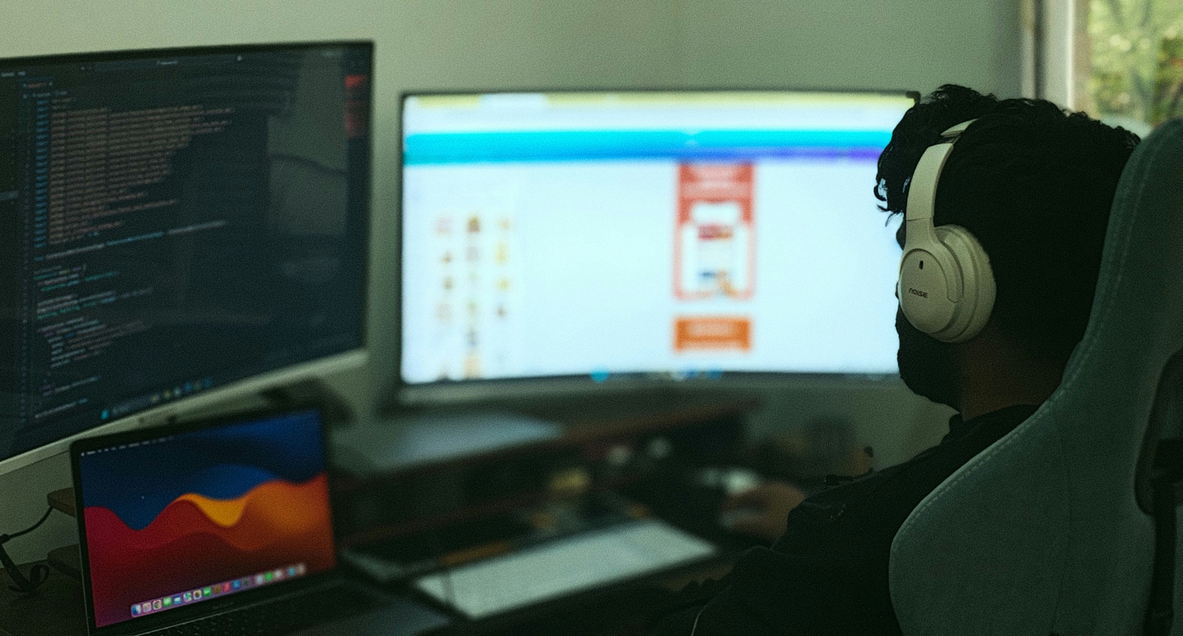 A person works on computer with multiple monitors.